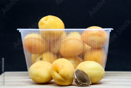 Many apricots lie in a plastic basket