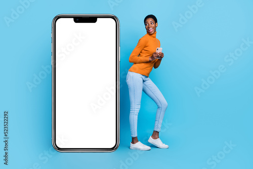 Full body photo of cheerful trans identity bi woman use smartphone see empty copy blank space isolated on blue color background