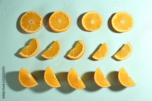 Cut fresh ripe oranges on light blue background, flat lay