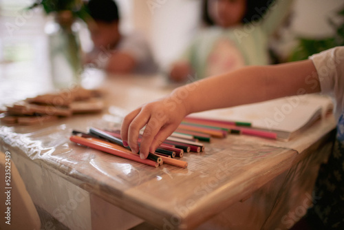 Girl reaching for colored pencil on table photo