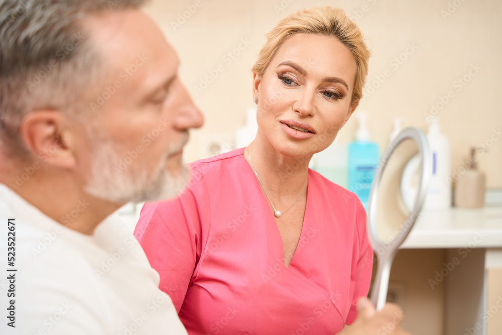 Man looks in mirror at consultation with beautician Man looks in mirror at consultation with beautician