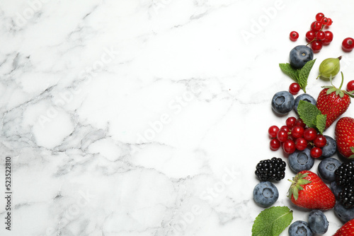 Mix of fresh berries on white marble table, flat lay. Space for text