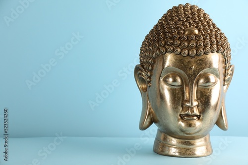 Beautiful golden Buddha sculpture on light blue background. Space for text