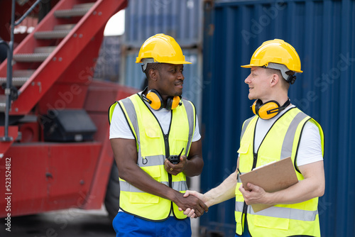 Caucasian businessman handshake with African worker in container port. Attractive male engineer people working and processes order at warehouse logistic in cargo freight ship import export in harbor.