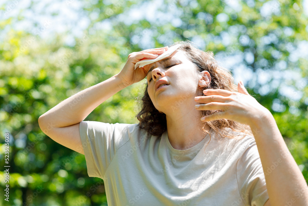 Young woman having hot flash and sweating in a warm summer day.