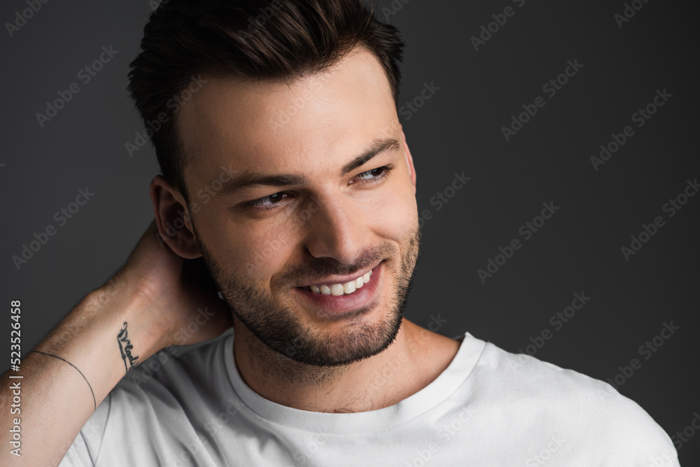 Portrait of brunette man smiling and looking away isolated on grey. Portrait of brunette man smiling and looking away isolated on grey.