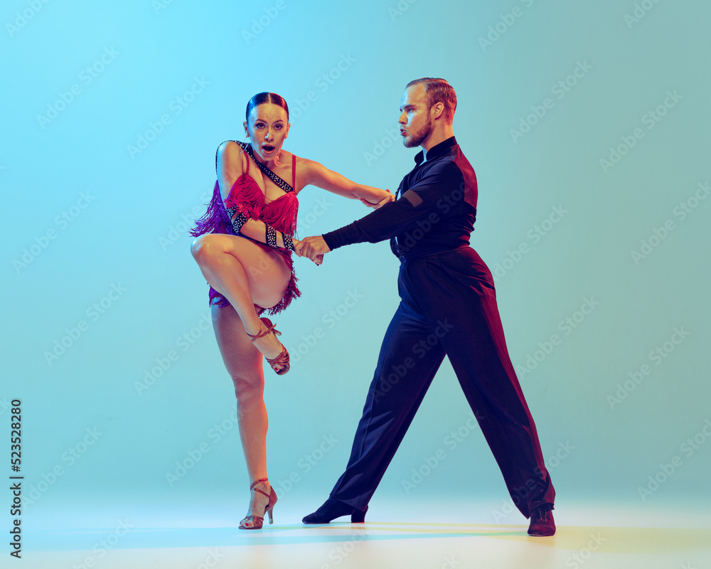 Obraz premium Beautiful woman and man, professional dancers dancing ballroom dance isolated on blue background. Concept of art, beauty, music, style.