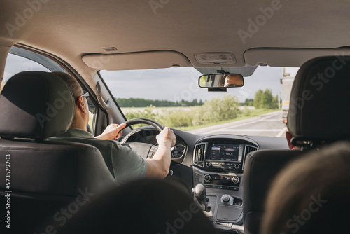 Young man holding steering wheel while driving car. Road trip. Local travel concept. Thirst for adventure. © Lyubov