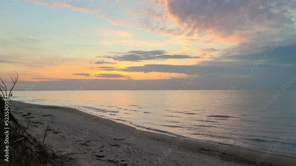 beautiful slide shot of a beach and ocean water washing on the sand at an orange sunset - wide shot beautiful slide shot of a beach and ocean water washing on the sand at an orange sunset - wide shot