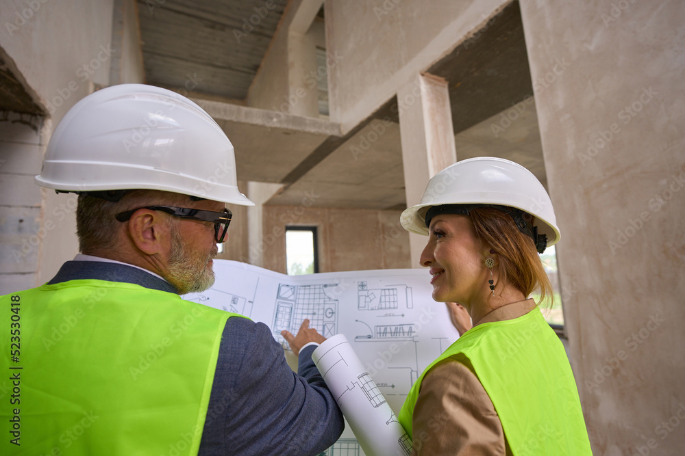 Foreman is discussing open drawing of house with handsome manager Foreman is discussing open drawing of house with handsome manager