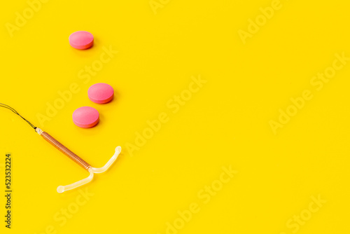 Contraception concept. T-shaped intrauterine contraceptive with medicine pills