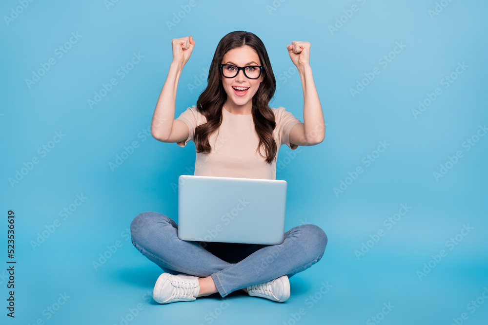 Photo of positive lady fist up win e shop lottery offer use netbook wear t shirt jeans isolated blue color background Photo of positive lady fist up win e shop lottery offer use netbook wear t shirt jeans isolated blue color background