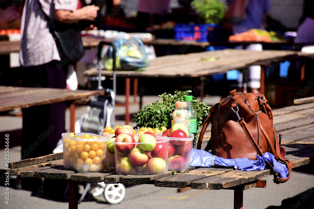 simple open vegetable market detail with apples and yellow tomatoes and green parsley. wooden display table. soft blurred background. organic fruit and vegetable concept. healthy eating. leather bag. simple open vegetable market detail with apples and yellow tomatoes and green parsley. wooden display table. soft blurred background. organic fruit and vegetable concept. healthy eating. leather bag.