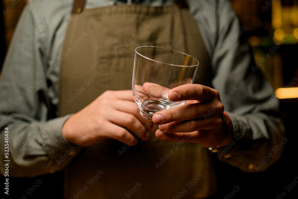 close-up view of caucasian male hand holding clean transparent empty glass for cocktail close-up view of caucasian male hand holding clean transparent empty glass for cocktail