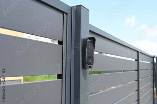 Black intercom call panel on a mounted in panel fence in anthracite color, visible wicket.Entrance to the private house.