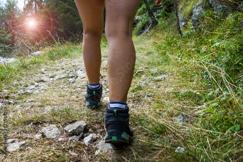 Young woman hiker trekking on a trail in a green forest on an adventurous and active vacation for a healthy and natural lifestyle concept in the nature of Italian Dolomiti mountains near Asiago 
