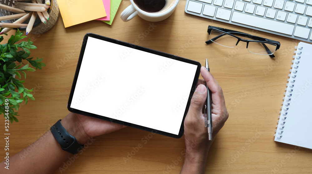Overhead view of businessman hands using digital tablet on wooden office desk. Overhead view of businessman hands using digital tablet on wooden office desk.