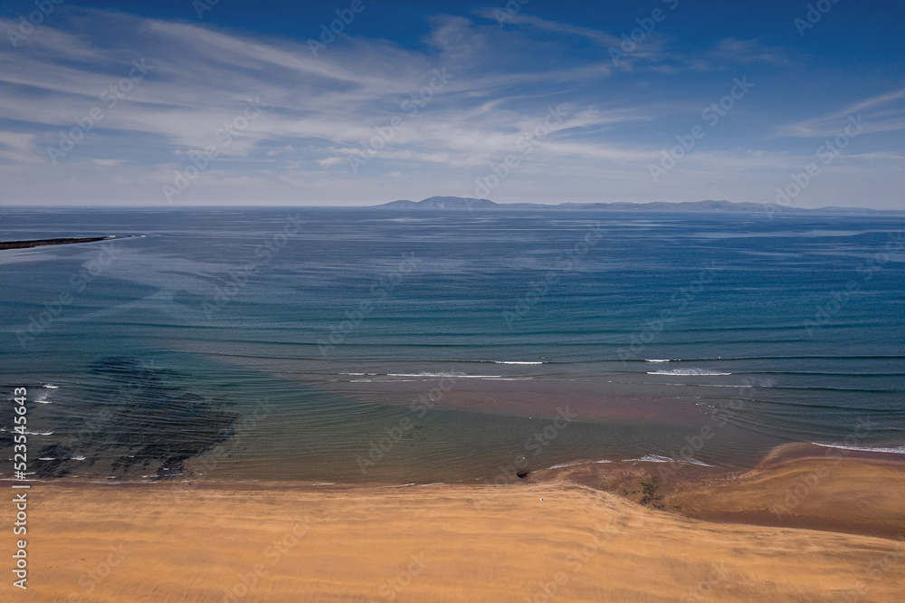 Aerial view on Streedagh beach in county Sligo, Ireland. Beautiful nature scene with warm yellow sand and blue ocean and clear blue sky. Popular tourist area. Warm sunny day. Aerial view on Streedagh beach in county Sligo, Ireland. Beautiful nature scene with warm yellow sand and blue ocean and clear blue sky. Popular tourist area. Warm sunny day.