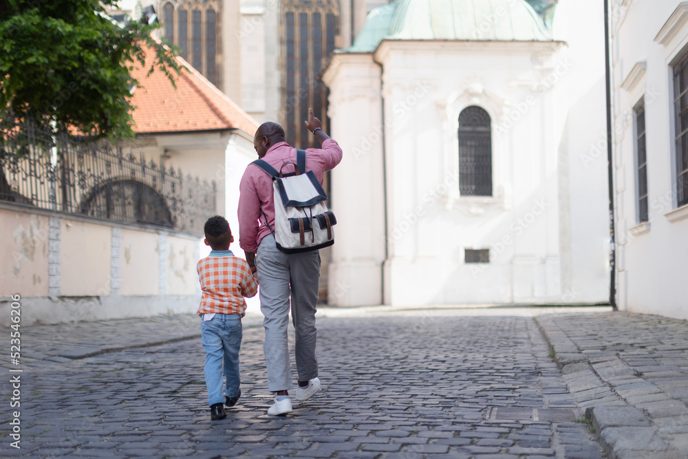Multiracial father with his son travelling together, walking in old city centre.