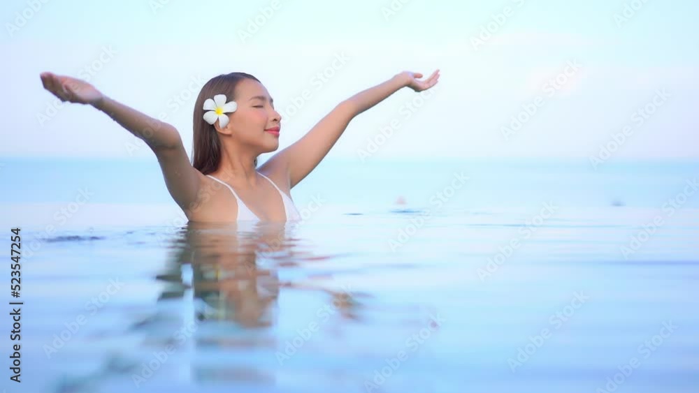 Close up of an attractive woman with a flower behind her right ear standing in a resort pool enjoying the warm water. Title space Close up of an attractive woman with a flower behind her right ear standing in a resort pool enjoying the warm water. Title space