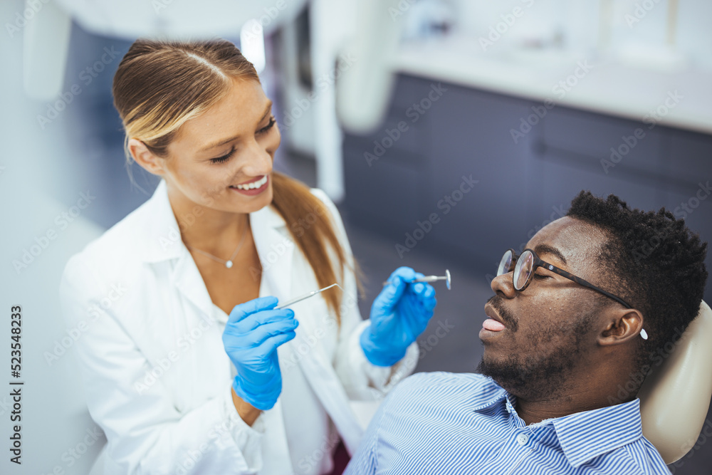 Black guy patient with open mouth having dental treatment from female doctor, close up. Man and female doctor while checkup teeth. Healthy lifestyle, healthcare and medicine concept. Black guy patient with open mouth having dental treatment from female doctor, close up. Man and female doctor while checkup teeth. Healthy lifestyle, healthcare and medicine concept.