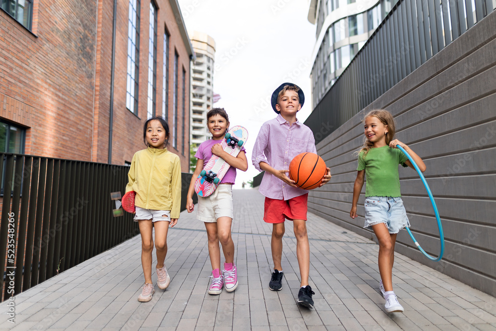 Obraz premium Happy kids playing and talking together in city, during summer day. Looking at camera, low angle view.