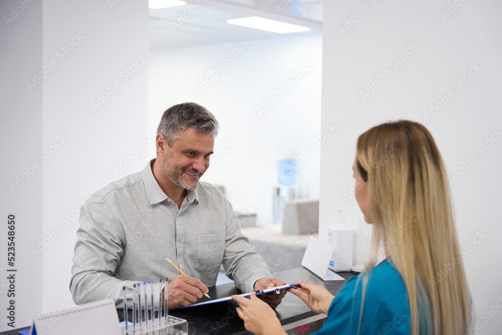 Fototapeta premium Doctor gives the patient to fill out a questionnaire