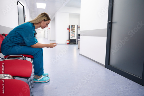 Woman in a blue doctor's suit sits on a chair