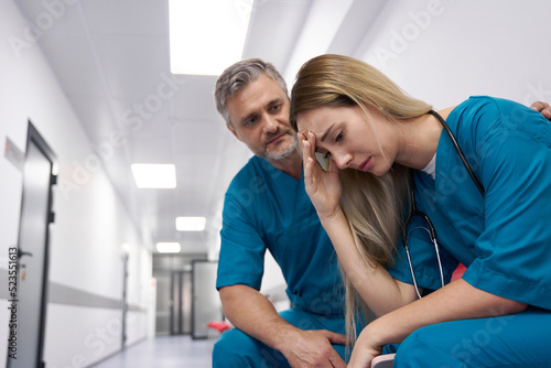 Male doctor in corridor comforting sad female doctor