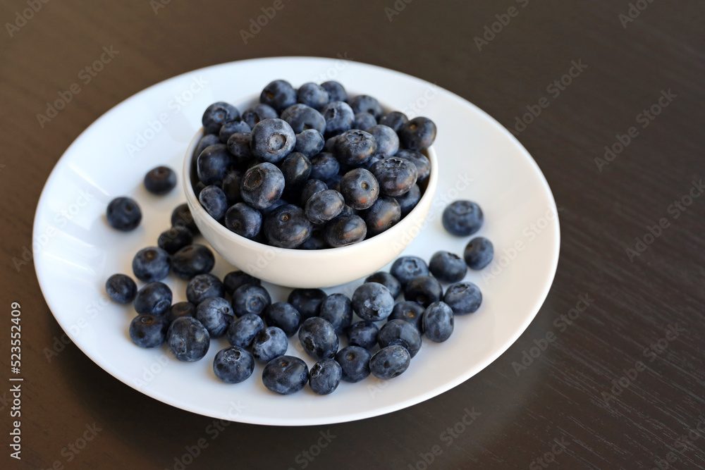 Fresh blueberry in a white plate on brown wooden table Fresh blueberry in a white plate on brown wooden table