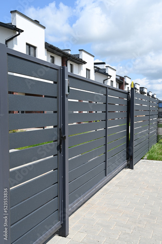 High grey fence. Modern barrier aluminum slats. Modern stone fence with metal shutters