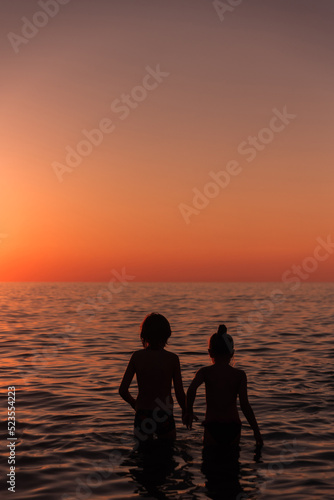Silhouette of a girl and a boy. Children at sunset at the beach