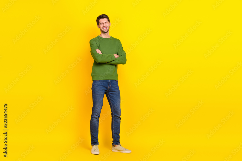 Fototapeta premium Photo of pretty charming guy wear green sweater arms crossed empty space isolated yellow color background