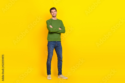 Photo of pretty charming guy wear green sweater arms crossed empty space isolated yellow color background