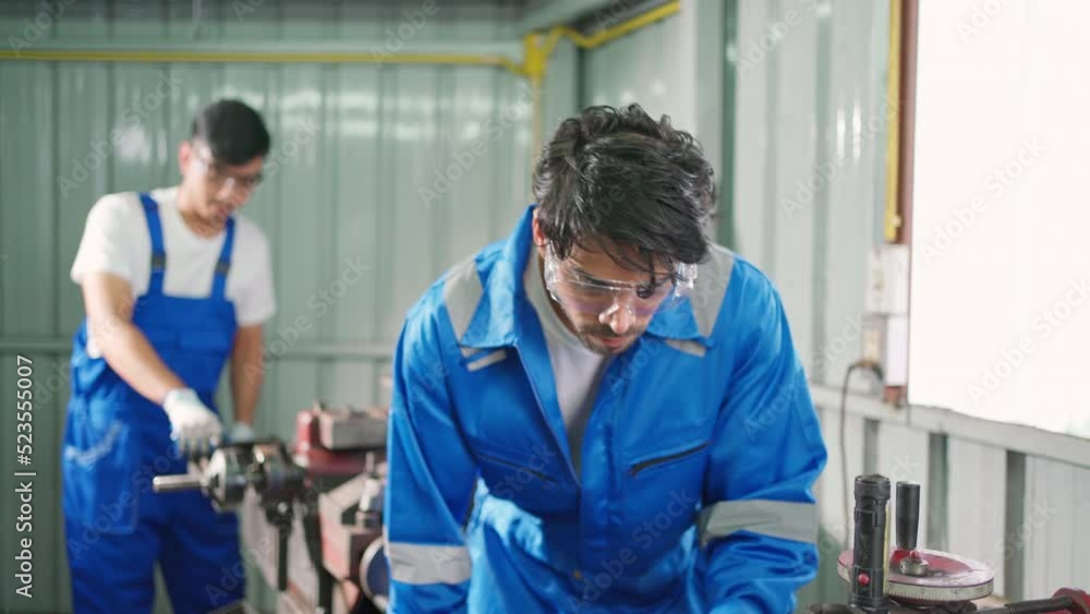 Mechanic man repairing brake disc of car using lathe tool polishing at garage. Engineer grinding machine brake disc to make flat surface. Maintenance and automotive industrial concept Mechanic man repairing brake disc of car using lathe tool polishing at garage. Engineer grinding machine brake disc to make flat surface. Maintenance and automotive industrial concept