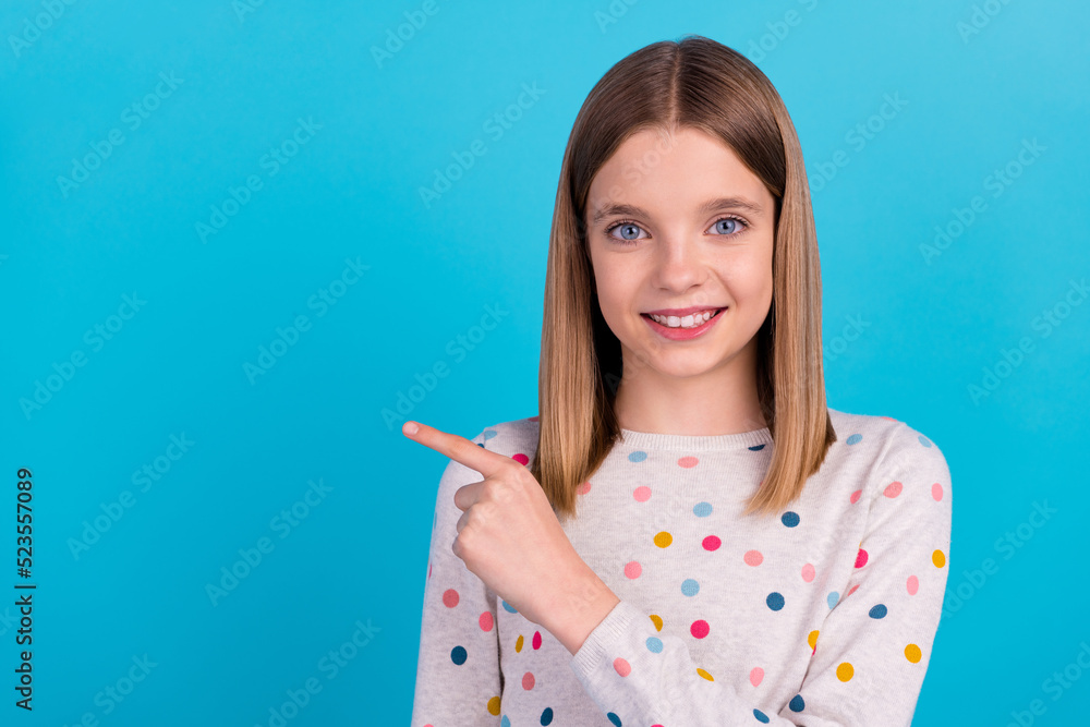 Photo of shiny cheerful little lady dressed dotted pullover pointing empty space smiling isolated blue color background Photo of shiny cheerful little lady dressed dotted pullover pointing empty space smiling isolated blue color background