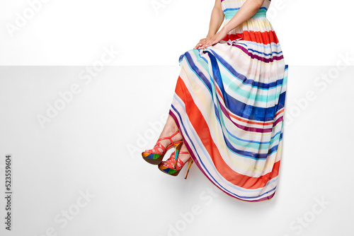 female legs wearing striped summer dress and pink high heels shoes
