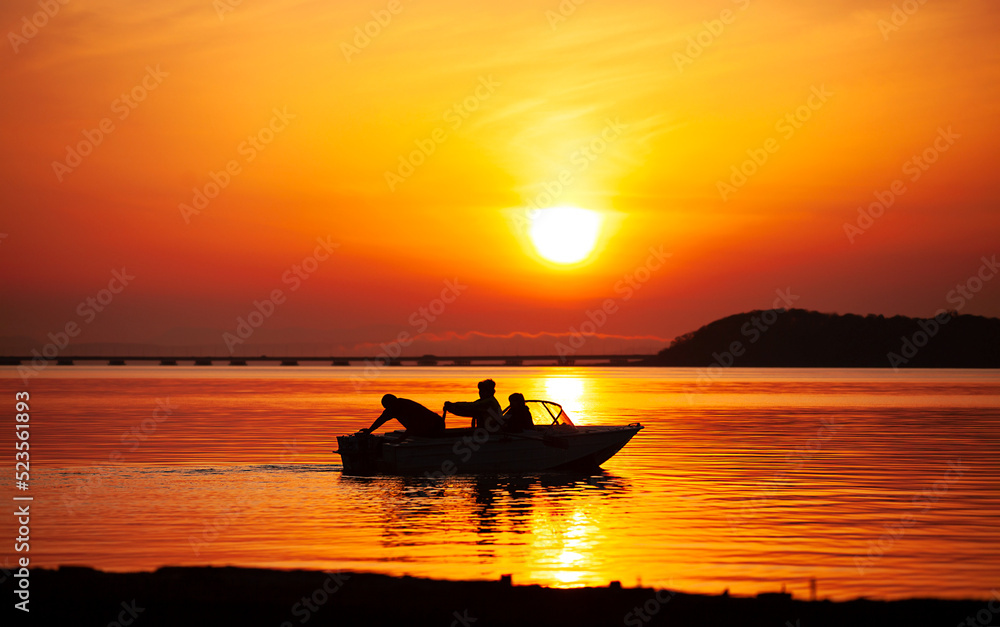 silhouette of a boat with fishermen mooring to the shore at sunset