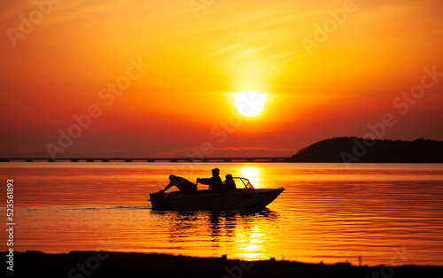 silhouette of a boat with fishermen mooring to the shore at sunset © Ольга Потылицына