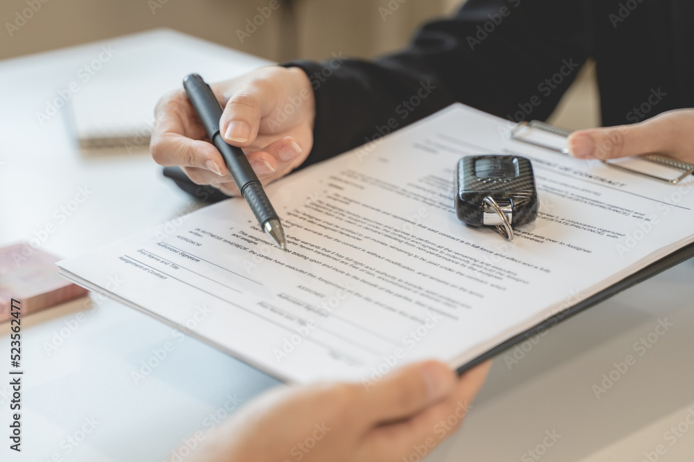 Car rental service concept. Close up view Hand of agent giving car key to customer after signed rental contract form. Car rental service concept. Close up view Hand of agent giving car key to customer after signed rental contract form.
