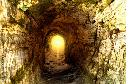 Fototapeta Naklejka Na Ścianę i Meble -  Sunlight at the end of a tunnel of rough hewn limestone, monochrome color scheme