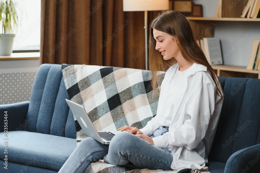 Full length portrait of cheerful charming person sit hold netbook browsing have good mood working home indoors Full length portrait of cheerful charming person sit hold netbook browsing have good mood working home indoors