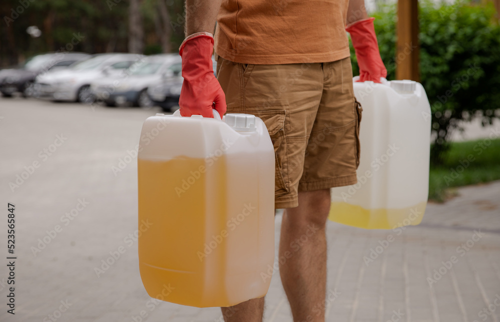 The man is holding cans of gasoline. Gasoline collapse. Fuel reserve for the car. Alternative method of filling the car