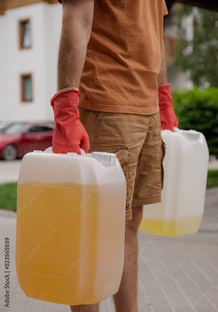 The man is holding cans of gasoline. Gasoline collapse. Fuel reserve for the car. Alternative method of filling the car