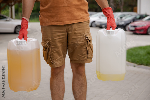 Obraz na płótnie The man is holding cans of gasoline. Gasoline collapse. Fuel reserve for the car. Alternative method of filling the car w salonie