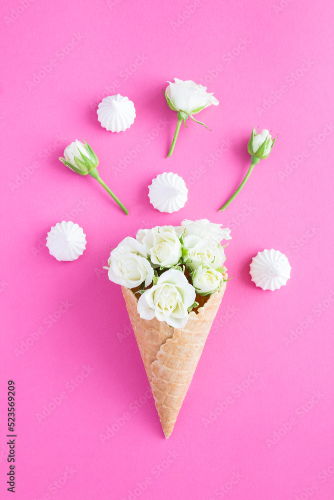 Ice cream cone with white roses and meringue the pink background. Closeup. Location vertical.
