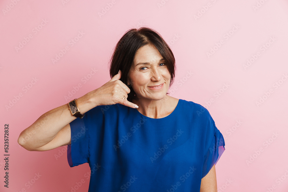 Mature brunette woman smiling while making handset gesture Mature brunette woman smiling while making handset gesture