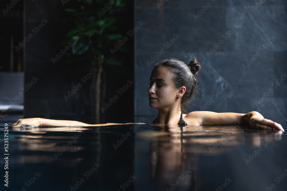 Attractive young woman in a black swimsuit is relaxing in the pool. Attractive young woman in a black swimsuit is relaxing in the pool.
