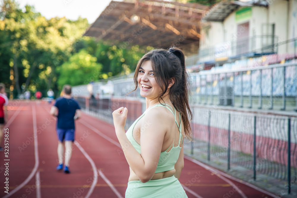 Attractive young woman in sportswear jogging at the stadium.