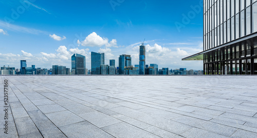 Empty square floor and city skyline with modern buildings under blue sky